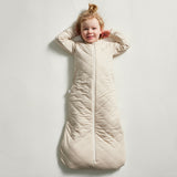 Child wearing a beige sleeping bag on a light gray background