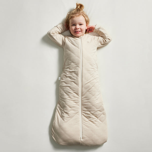 Child wearing a beige sleeping bag on a light gray background