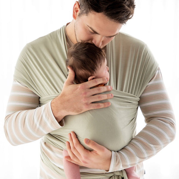 Model wears KYND Baby Sling in Sage Green